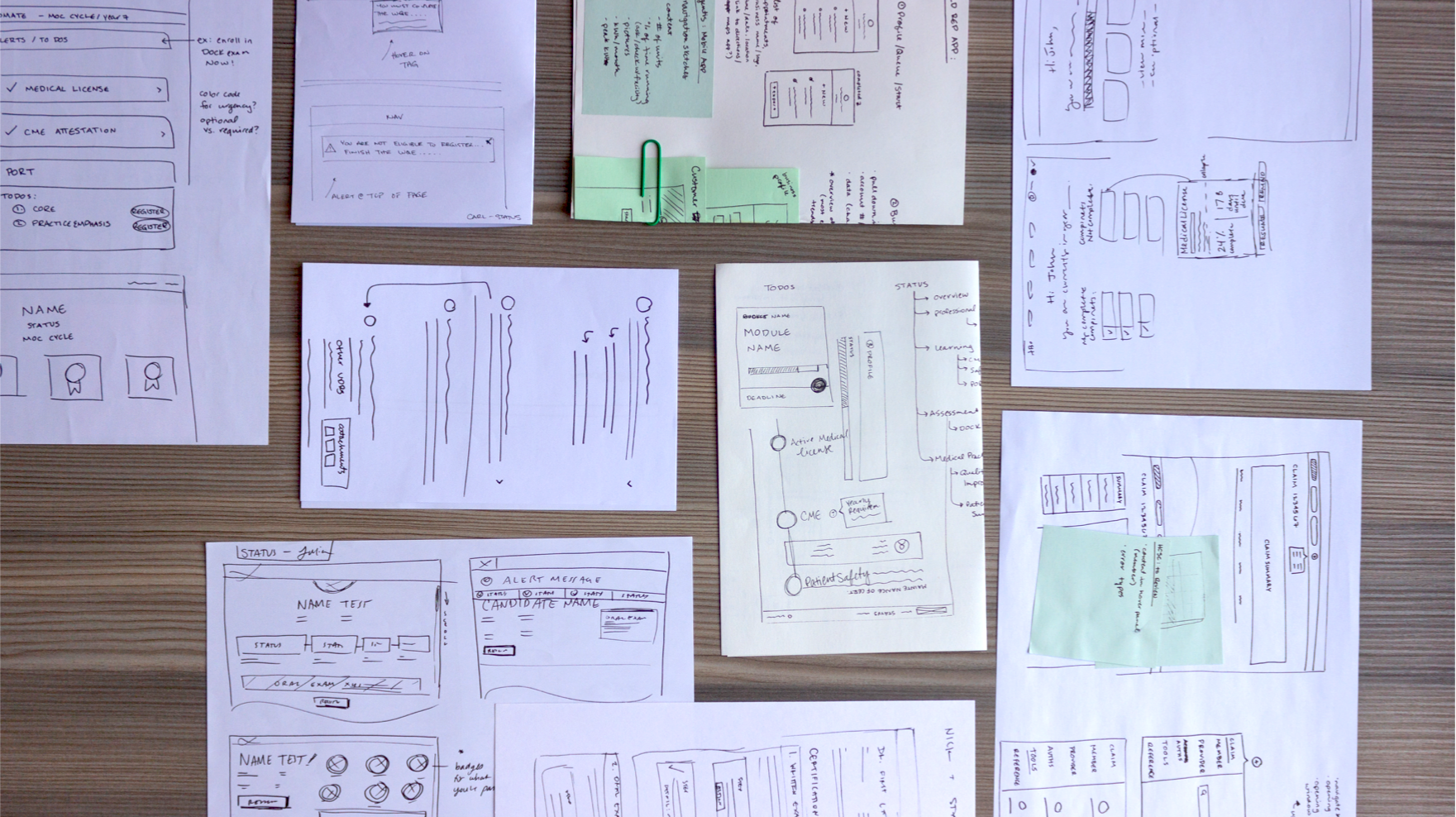 A tabletop covered in wireframe sketches to describe enterprise UI design systems