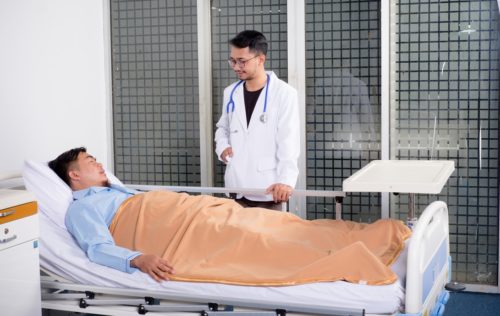 A doctor speaking with a patient in a hospital bed. Doctors can also benefit from the use of healthcare technology