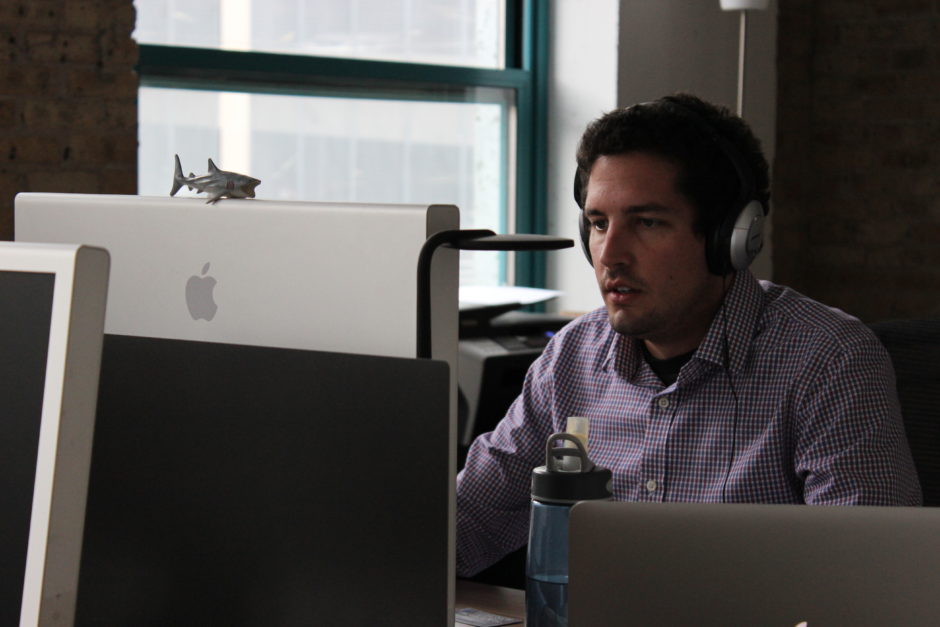 A man with headphones on working at his computer screen.