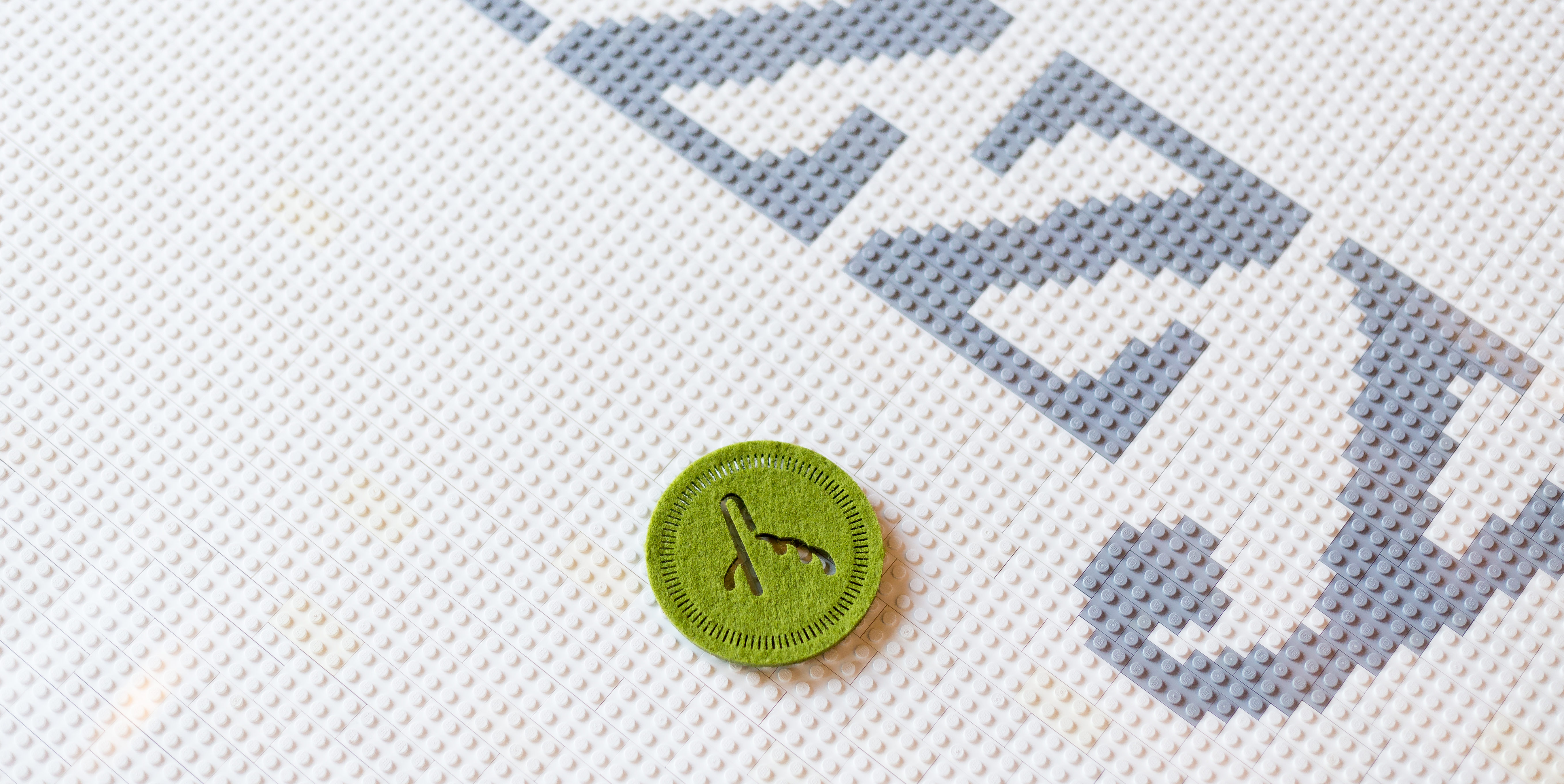 Green Fuzzy Math logo coaster on table made of Legos