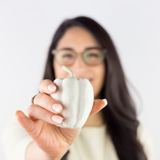 Paris smiling and holding a ceramic bell pepper