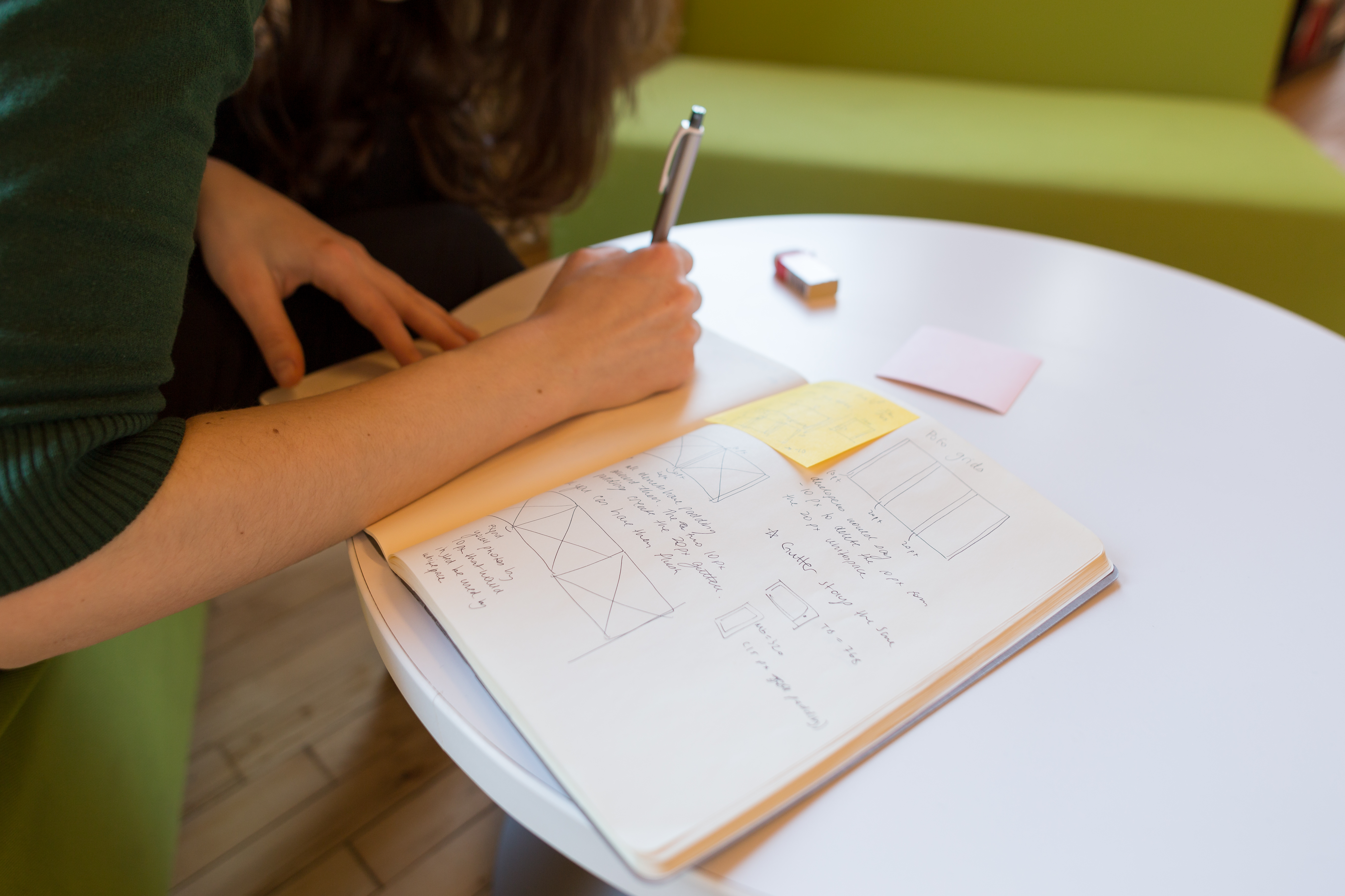 A UX design team of one is working alone, sketching in a notebook