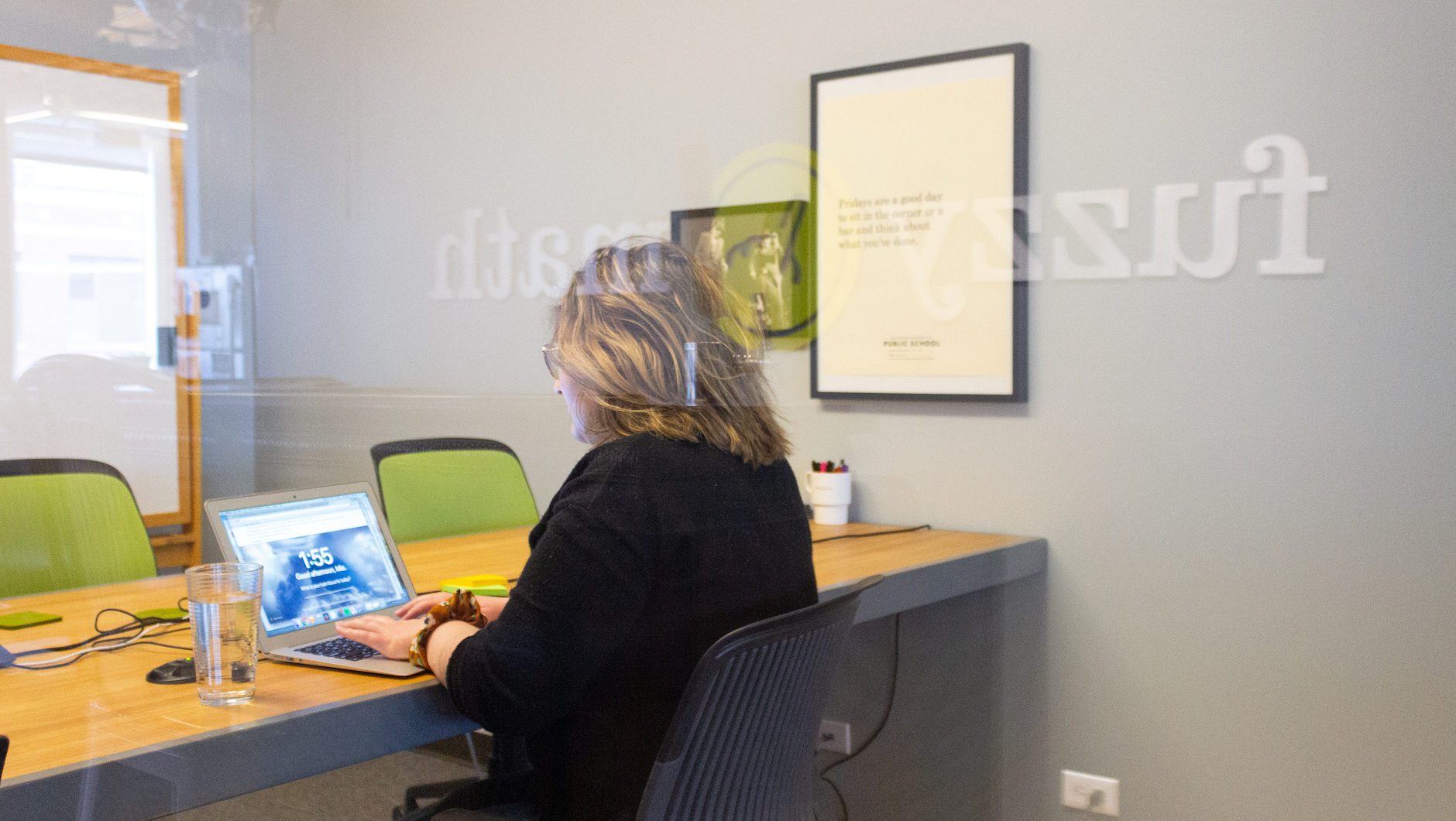 A day in the life of a UX designer includes time in meetings. A UX designer sits at a conference room table, looking at a laptop computer in front of her.