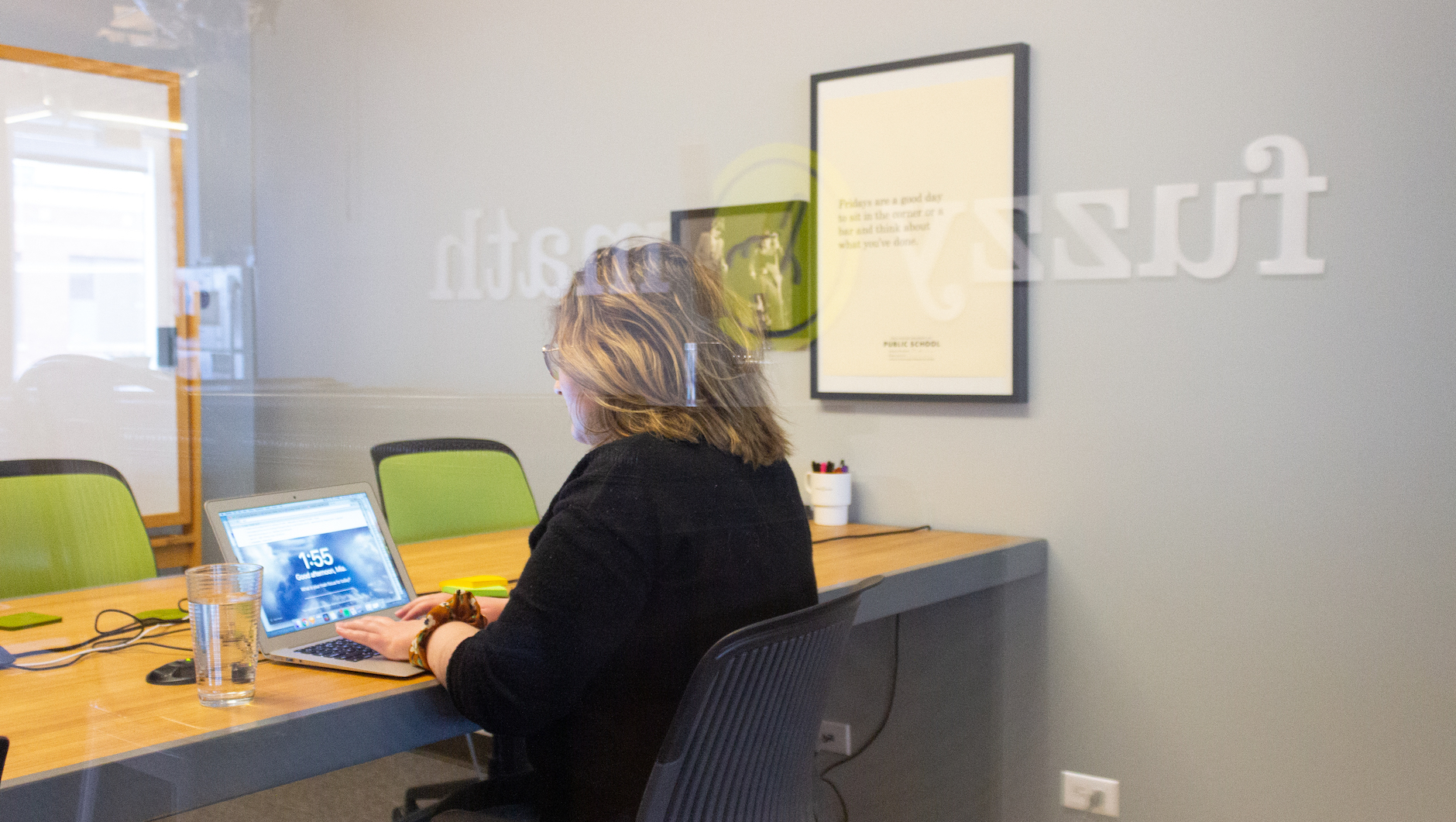 A day in the life of a UX designer includes time in meetings. A UX designer sits at a conference room table, looking at a laptop computer in front of her.