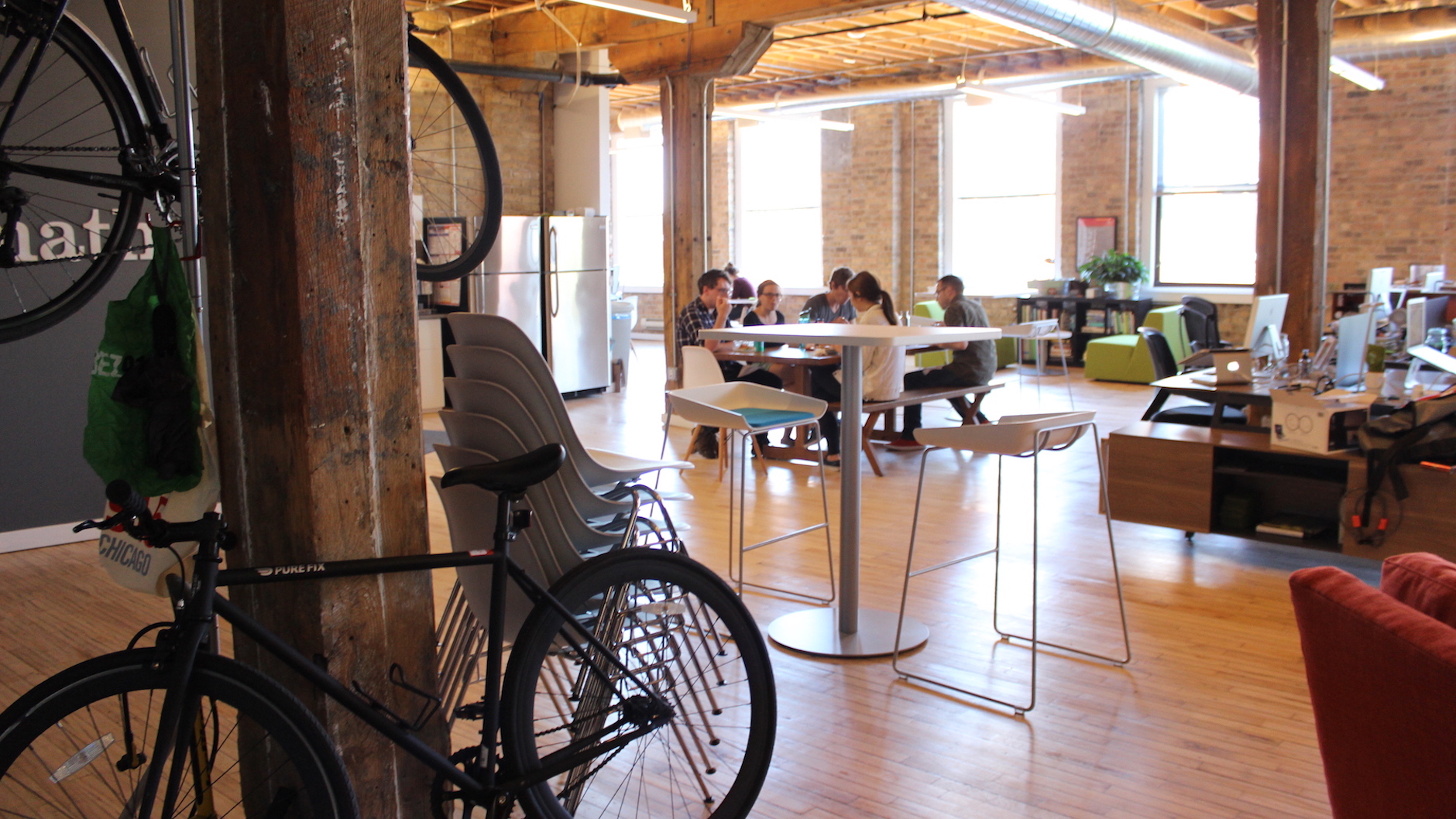 An interior view of the Fuzzy Math office, with several designers sitting at a table together. Fuzzy Math designers often collaborate with in-house design teams in order to provide greater value to their clients.