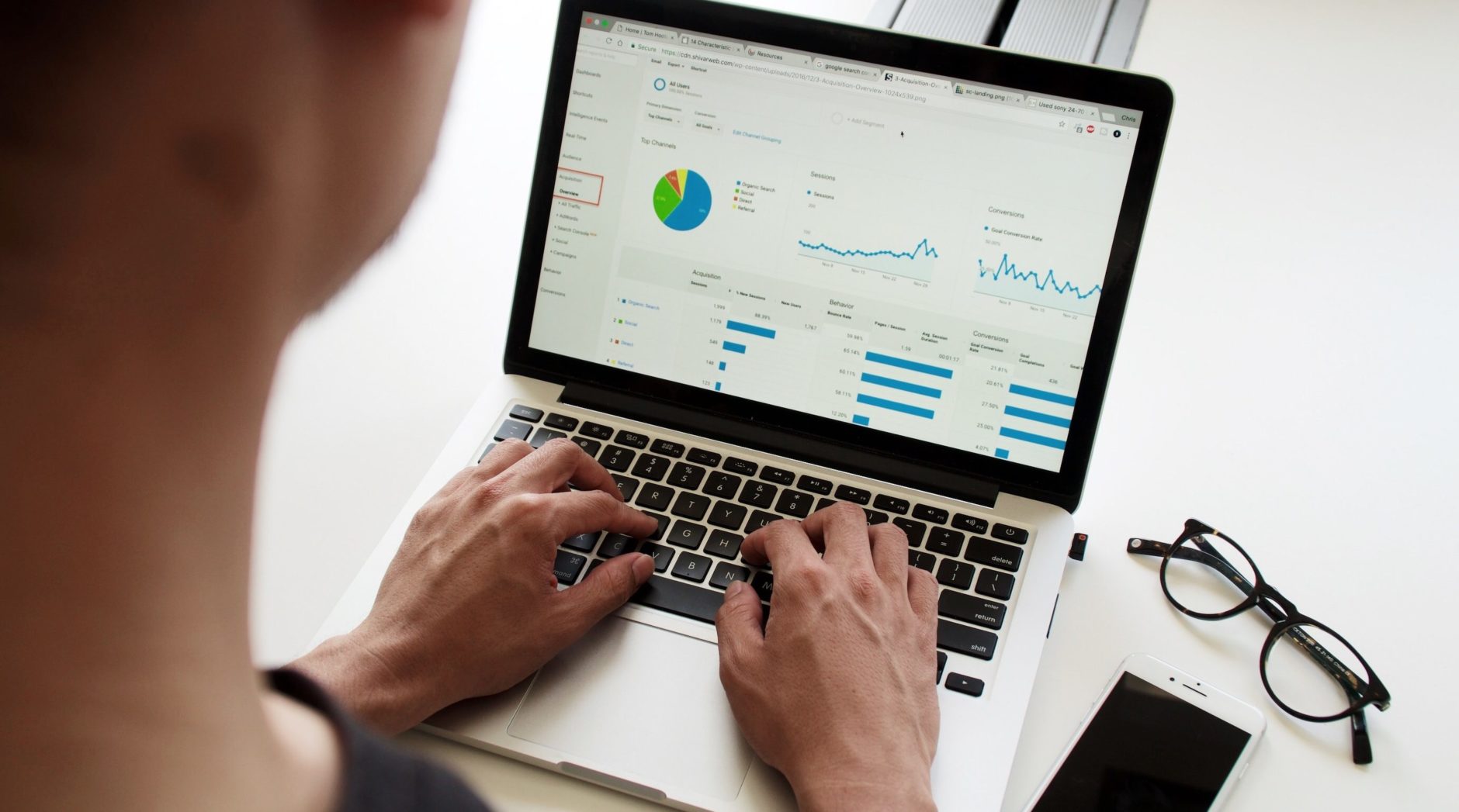 Over-the-shoulder view of a computer screen with various charts and graphs to illustrate a business leader monitoring KPIs for your design department