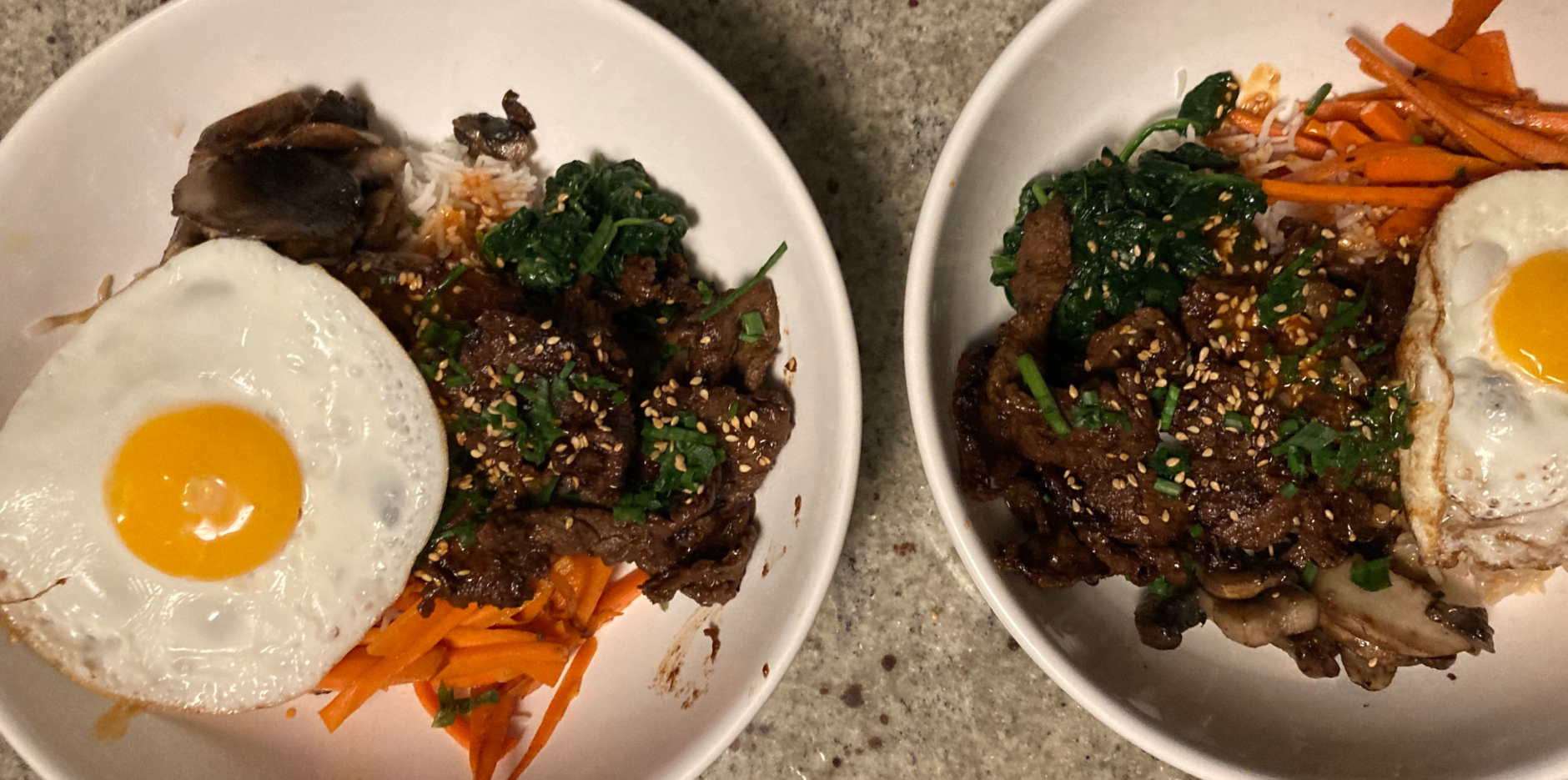 A top-down photo of two bowls of bibimbap with a sunnyside up egg on top.