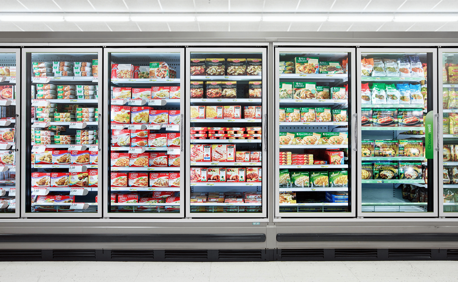 A picture of a refrigerated aisle at a grocery or convenience stores. Glass clad cooler cases showcase the food inside.