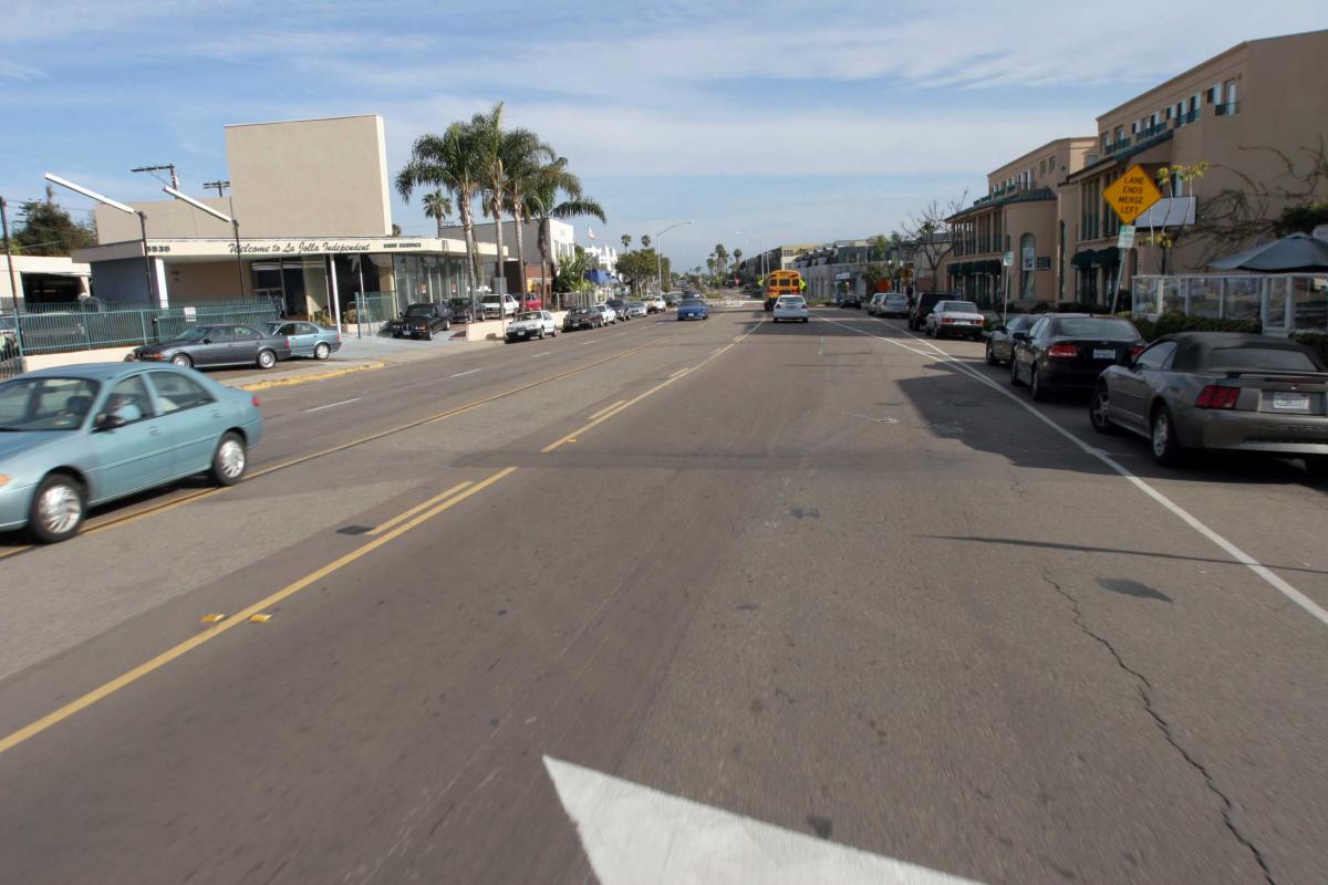 A before picture a stroad, gray with fast moving cars and not a lot of pedestrian space