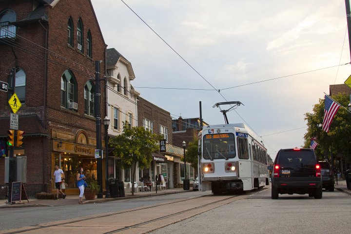 A picture of a quaint semi-urban commercial corridor with a streetcar running through it.
